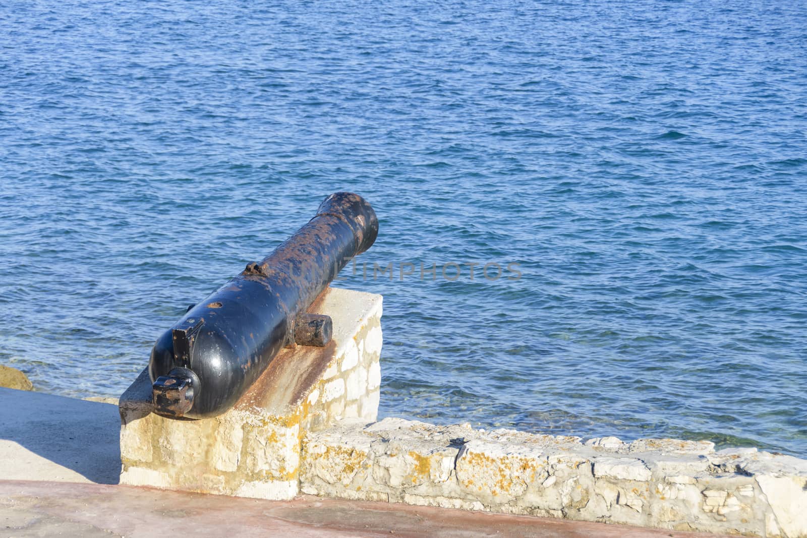 Ancient old cannon on coastal fortress walls aiming to the sea; fortress defense