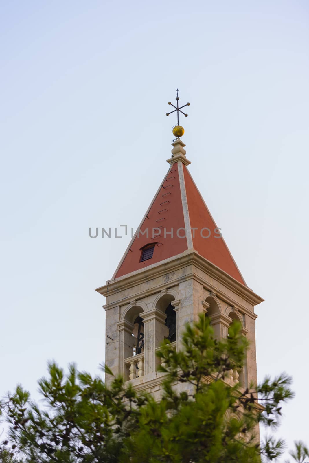 Christian church steeple in front of pines on blue sky by asafaric