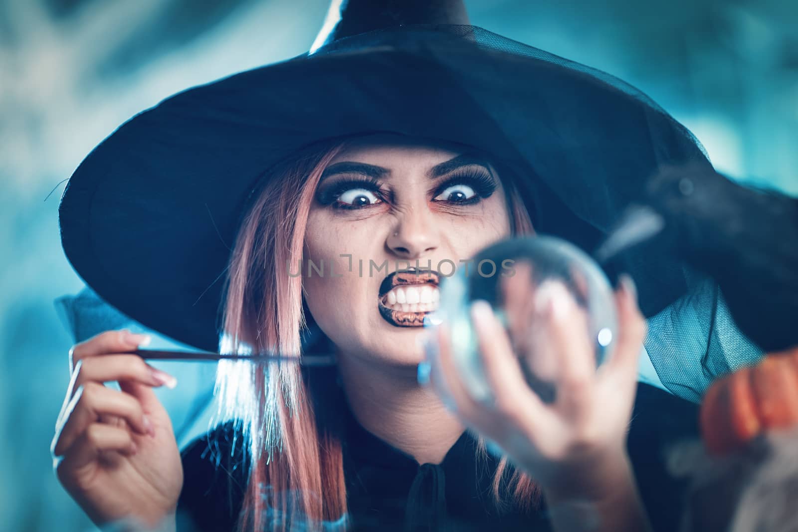 Portrait of angry witch watching the future in magic ball. Selective focus. Focus on witch.