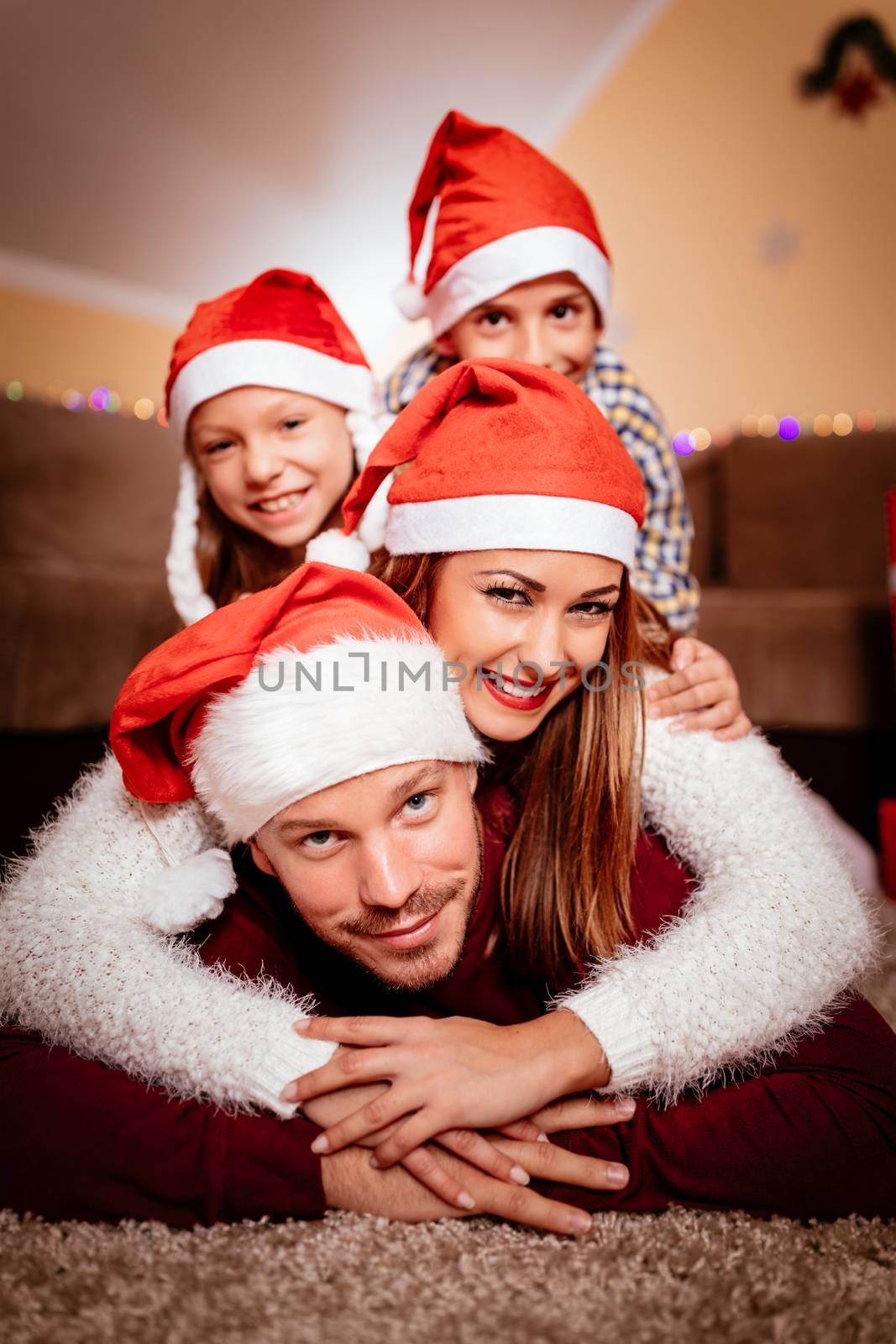 Beautiful smiling family with santa hat having fun in Christmas eve at the home. Looking at camera. 