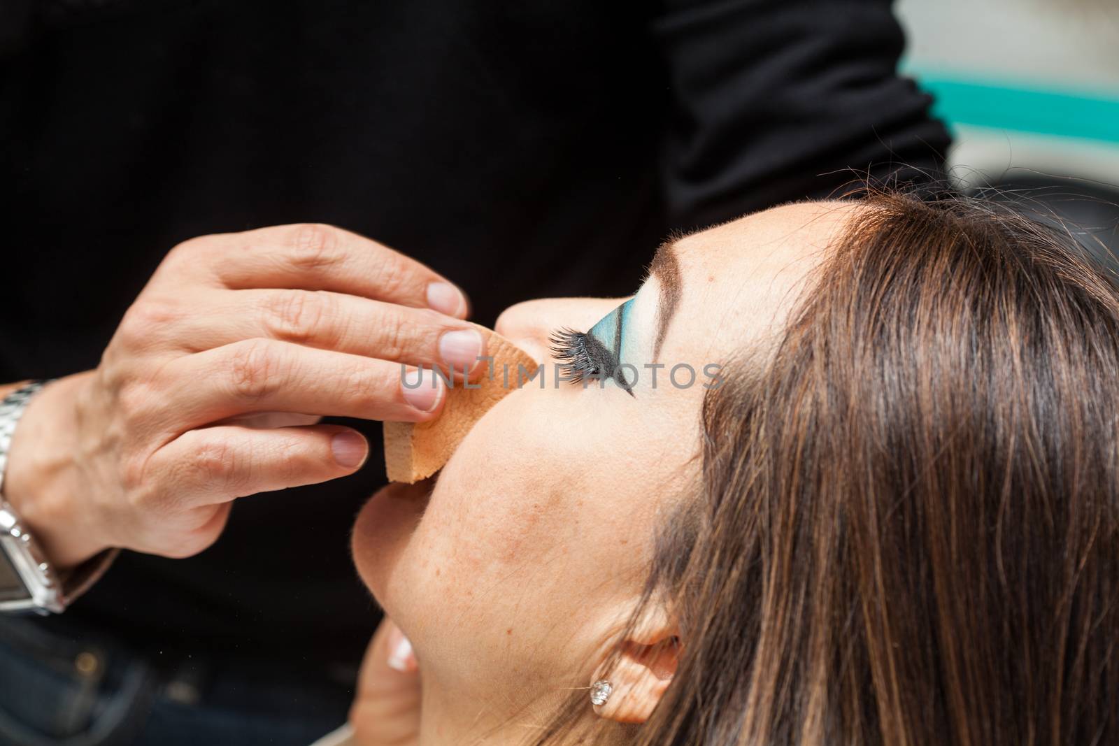 Makeup artist applying foundation using a sponge to a white woman