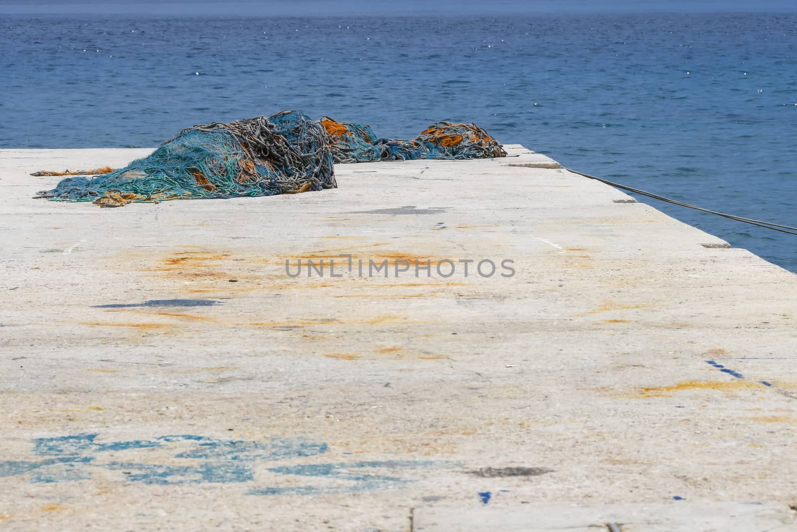 Concrete pier with blue and brown fishing nets lying around