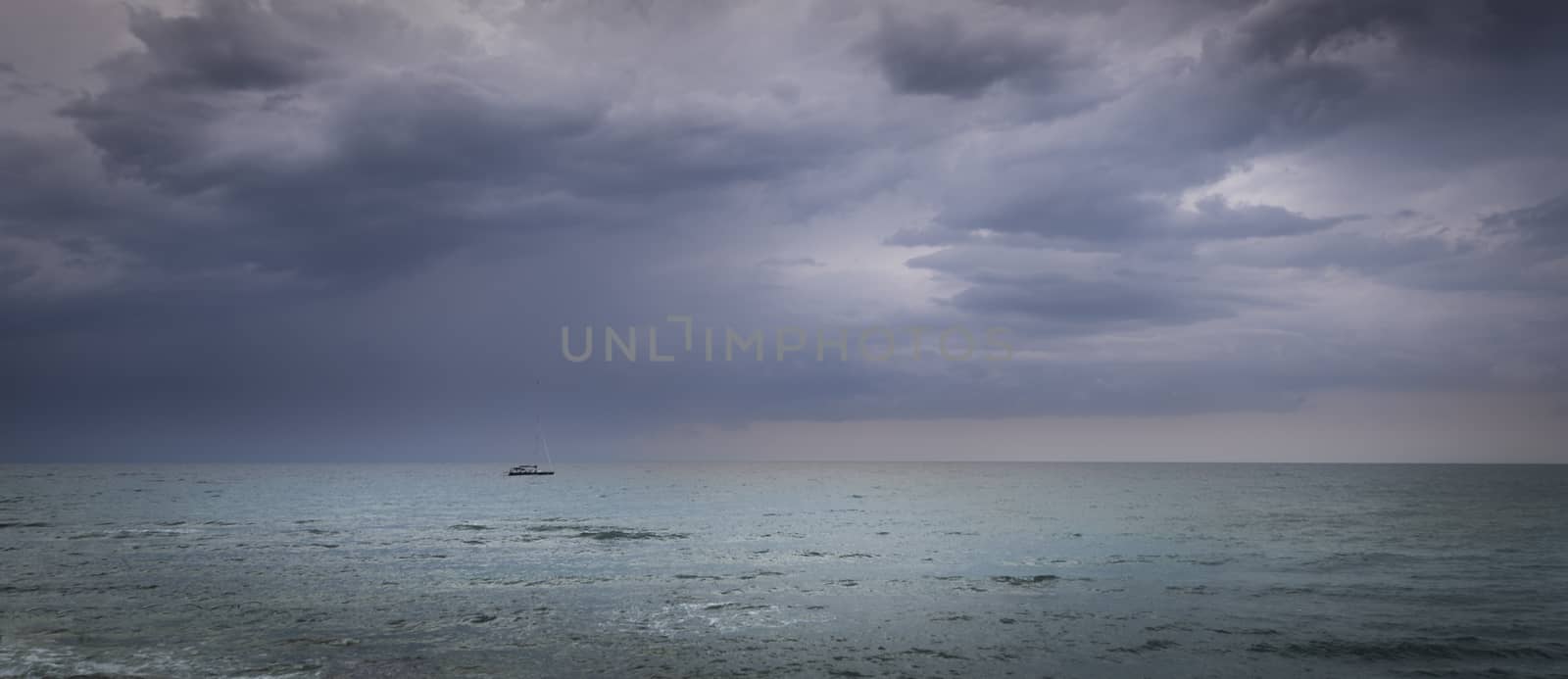 Sailboat in open sea and astorm approaching, dramatic skies, calm sea