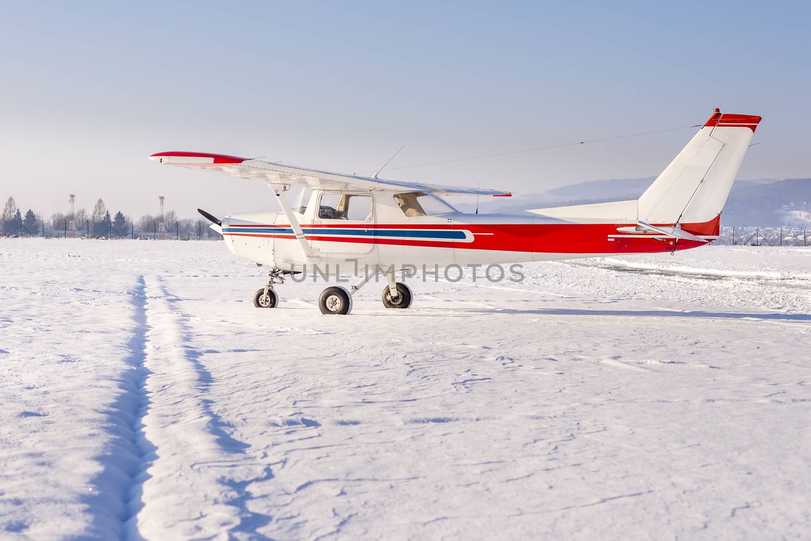Small sports plane in winter at snow covered airport by asafaric