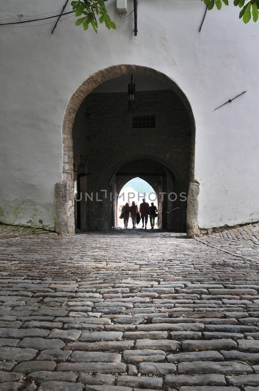 View of old city gate and tourists passing through the gate in historic istrian town of Motovun, Croatia.