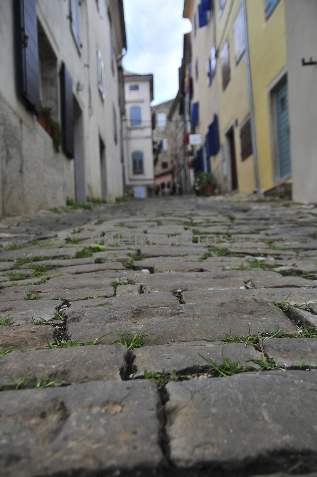 Detail of street stone pavement in a medieval town, houses and buildings in background out of focus for effect