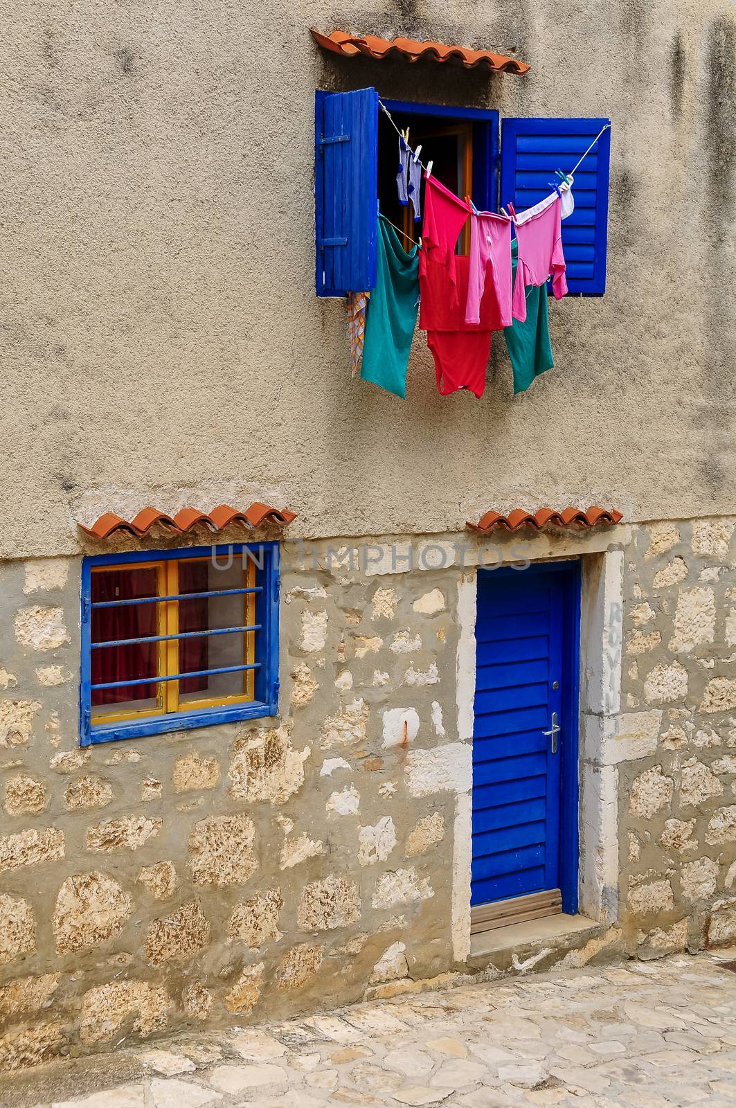 Laundry driying in sun, blue windows and blinds by asafaric