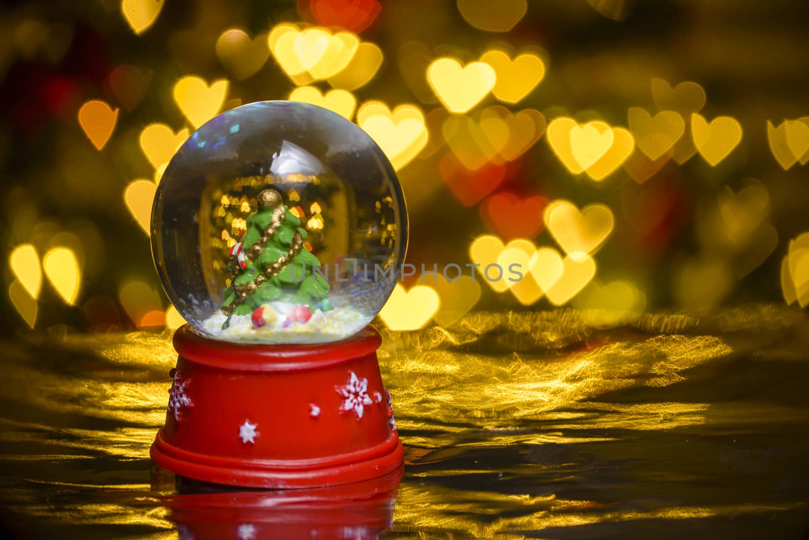 Christmas snow globe with xmas lights in background; decorated christmas tree; heart shapes bokeh blur