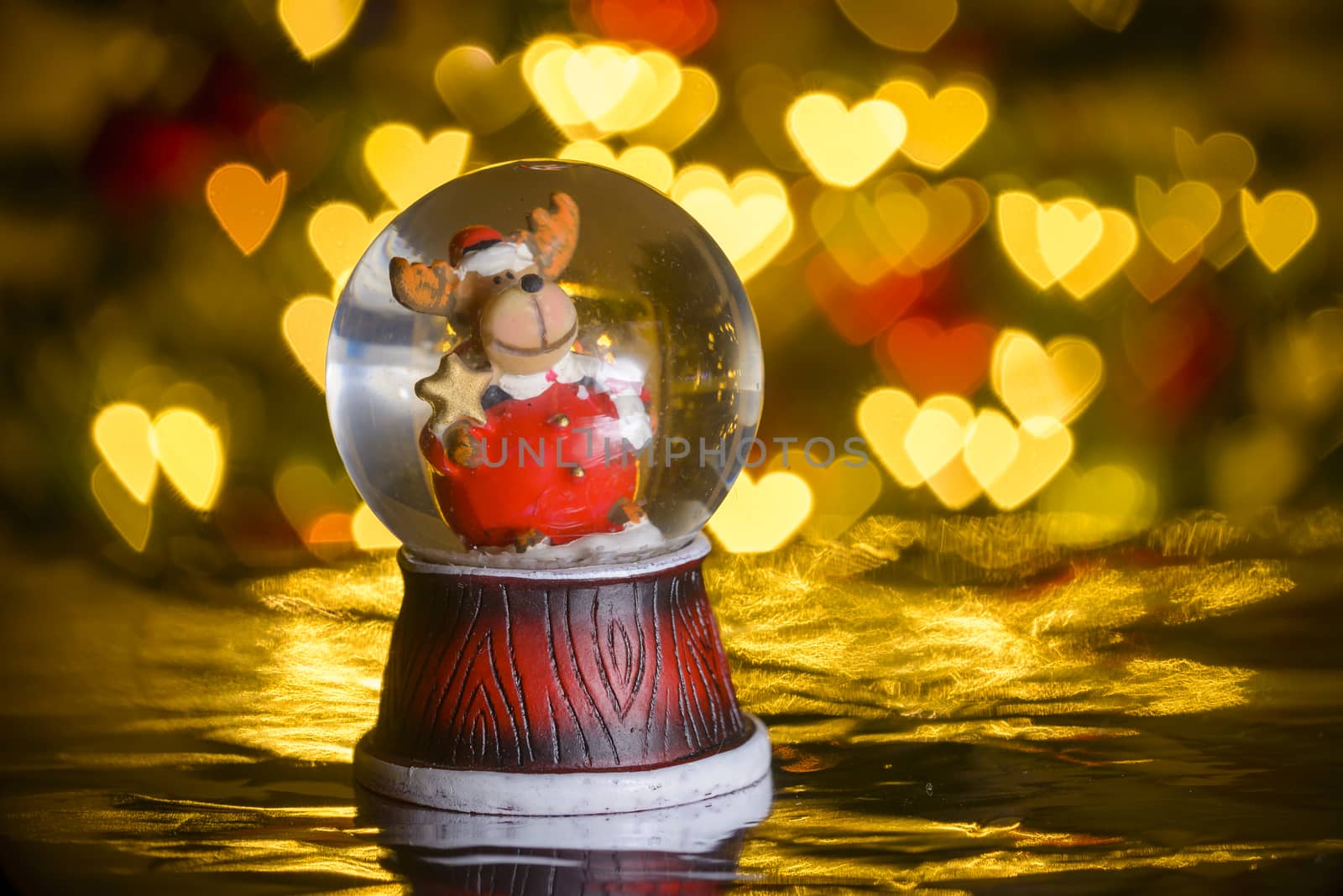 Christmas snow globe with xmas lights in background; reindeer in santa apparel; heart shapes, bokeh blur
