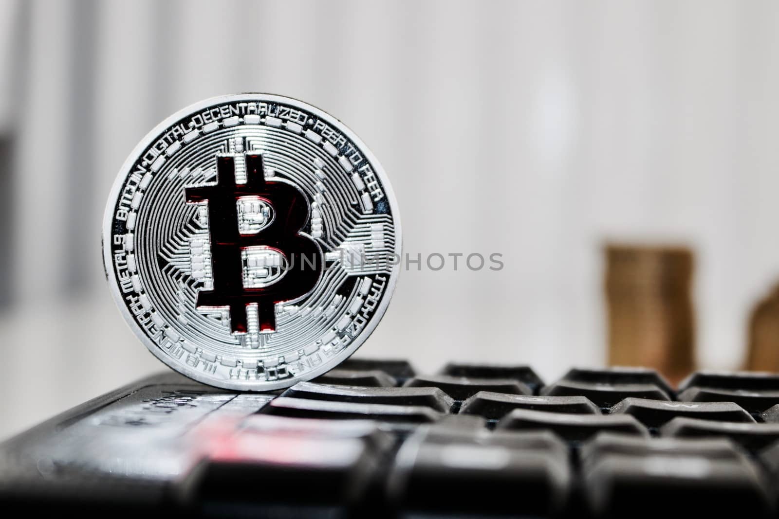 Digital currency physical silver bitcoin coin with red sign on the black computer keyboard.
