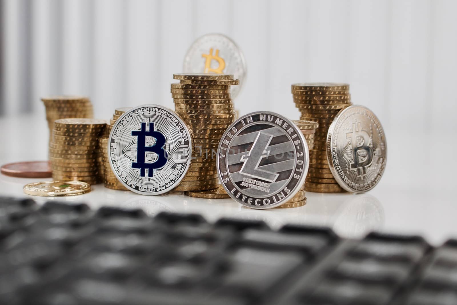 Digital currency physical silver bitcoin coin and silver litecoin near money and black computer keyboard.
