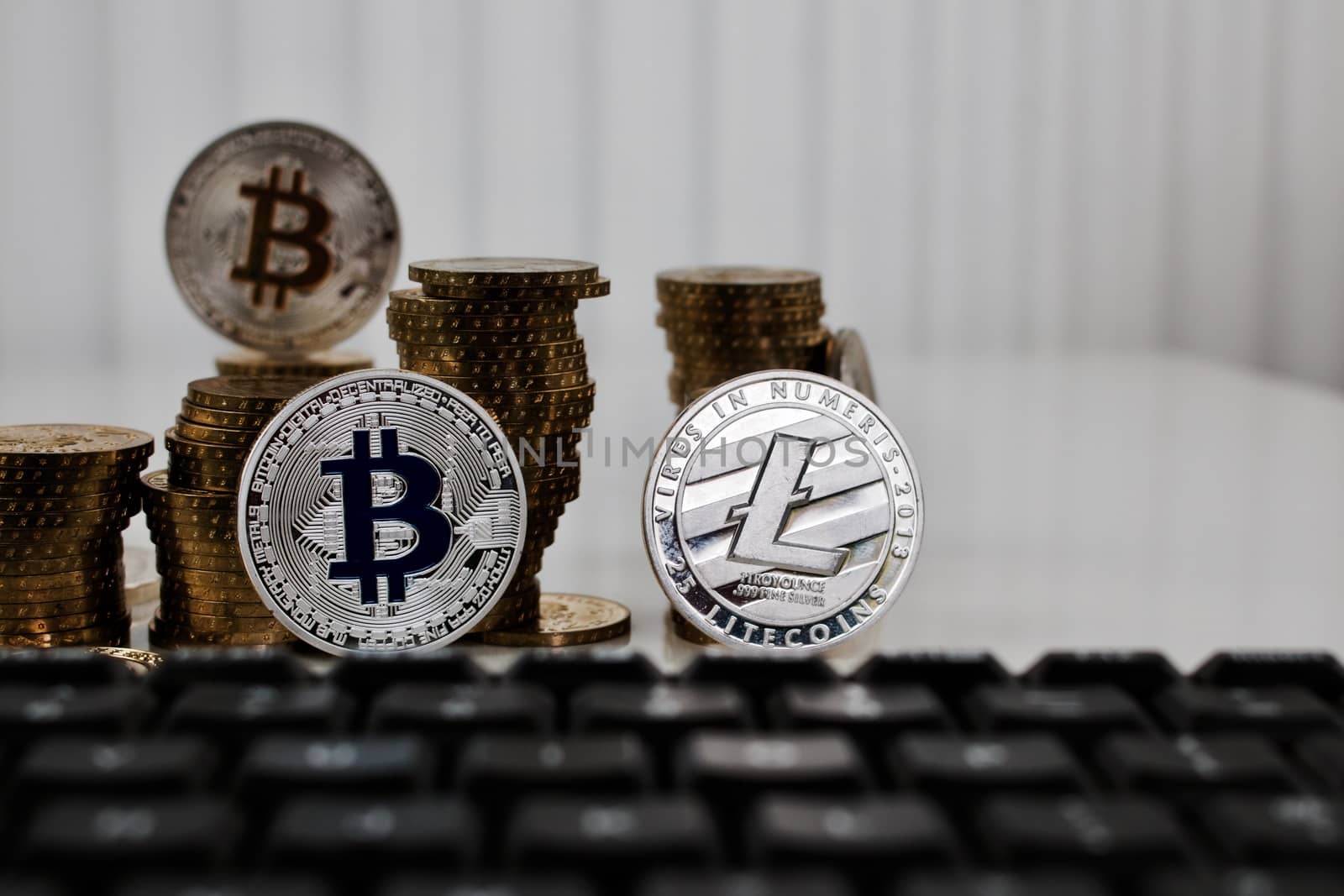 Digital currency physical silver bitcoin coin and litecoin near black keyboard.
