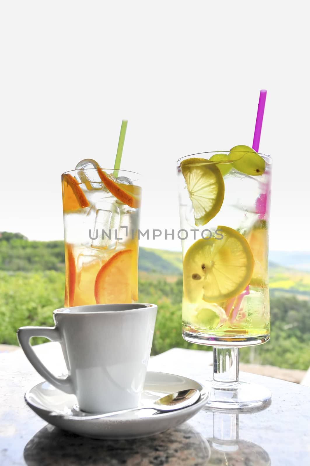 A cup of coffee and two glasses of lemonade on table, tranquil scenery in background