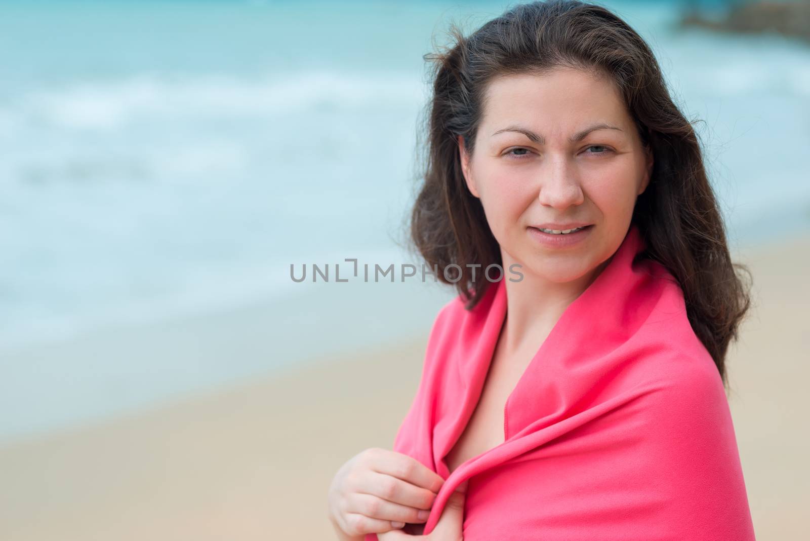 portrait of a brunette woman wrapped in a towel at the beach