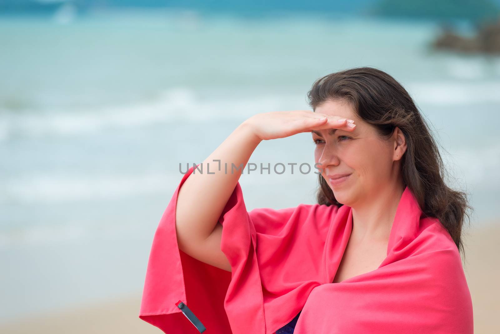 brunette girl in a pink towel on the beach in the morning
