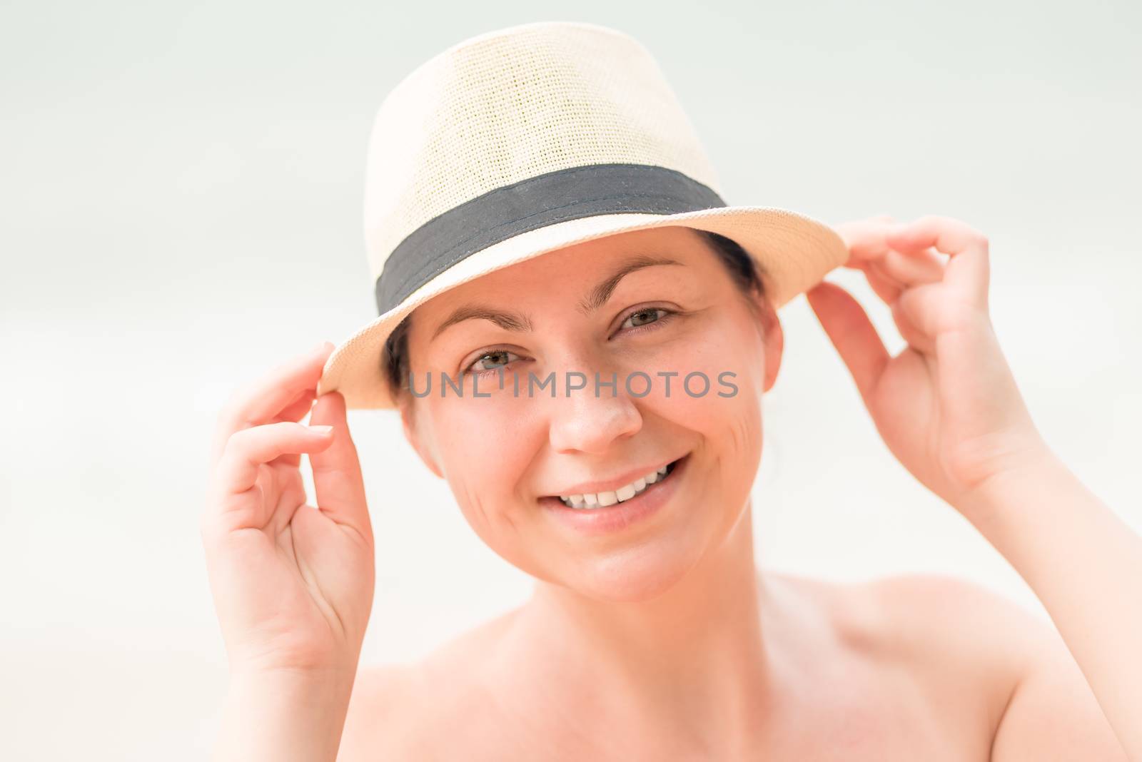 close-up portrait of a woman on the beach wearing a straw hat