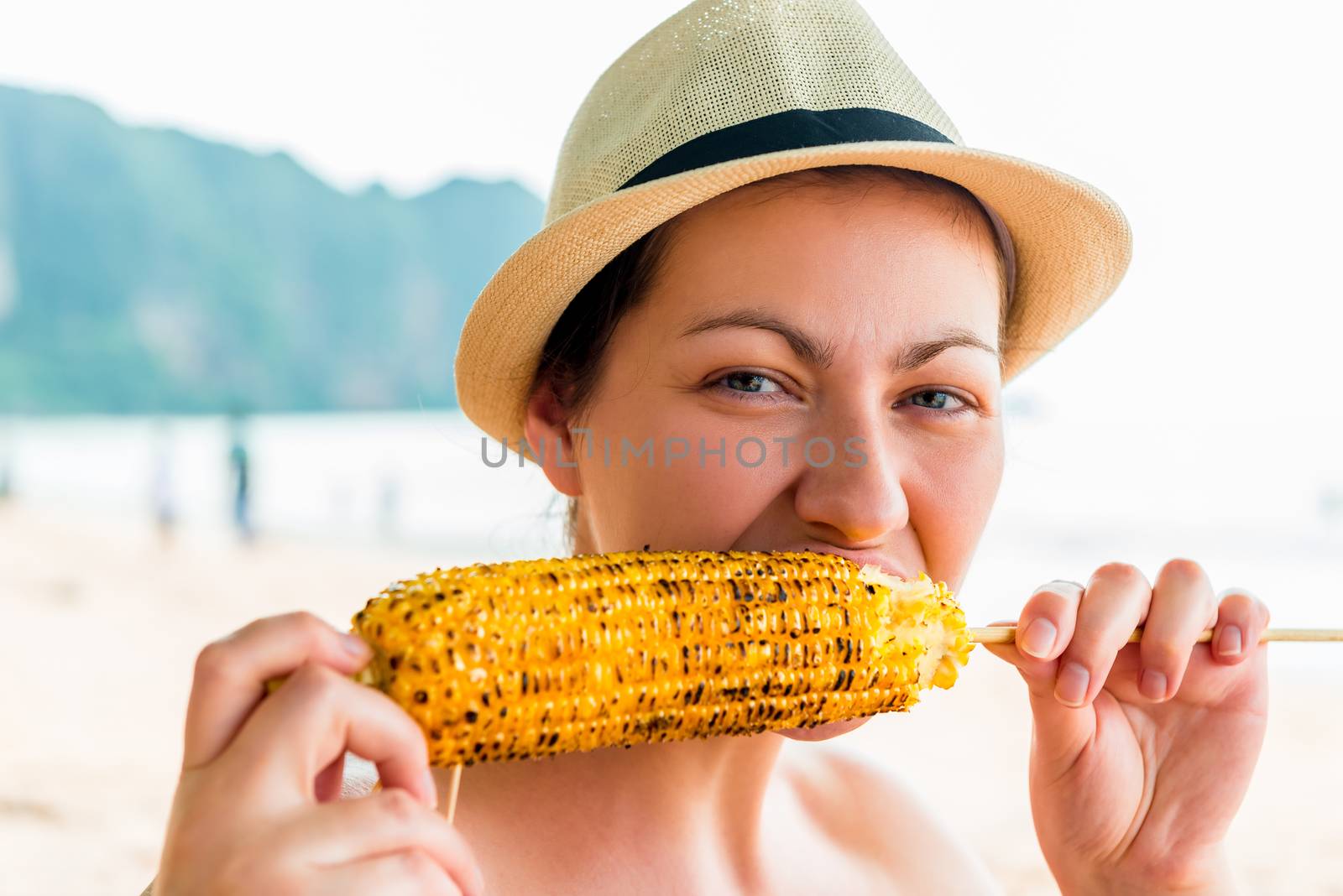 portrait of a woman with a delicious corn grill on the beach