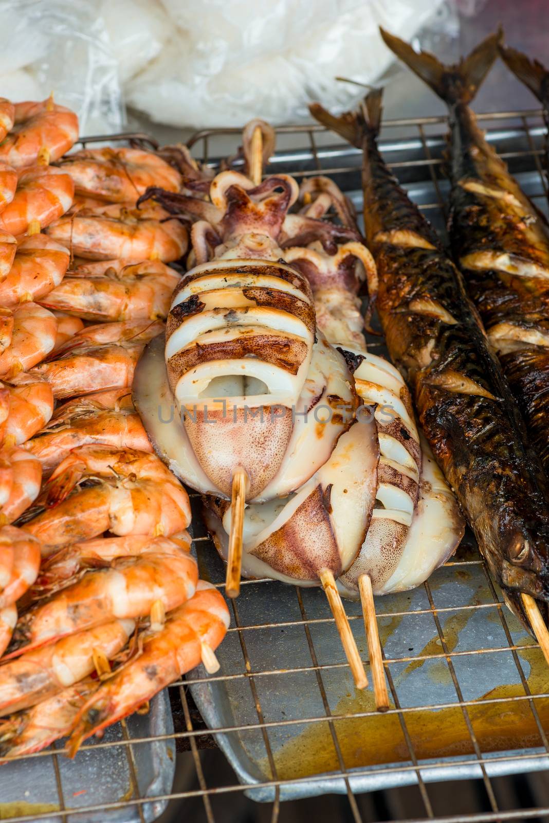 closeup grilled shrimp, squid and fish fresh sea food on the streets in Thailand