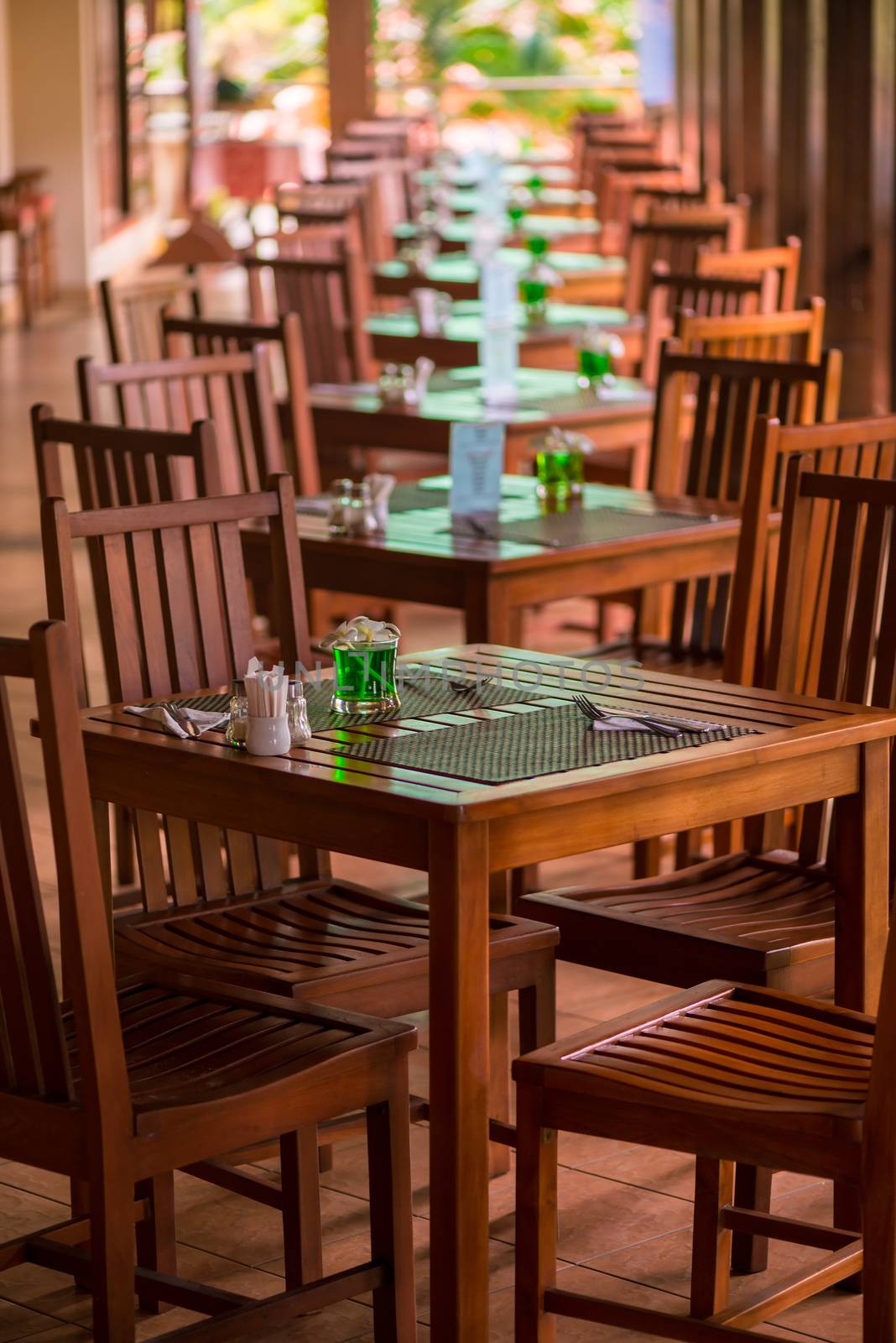 tables stand in a row on an open veranda in the tropics by kosmsos111