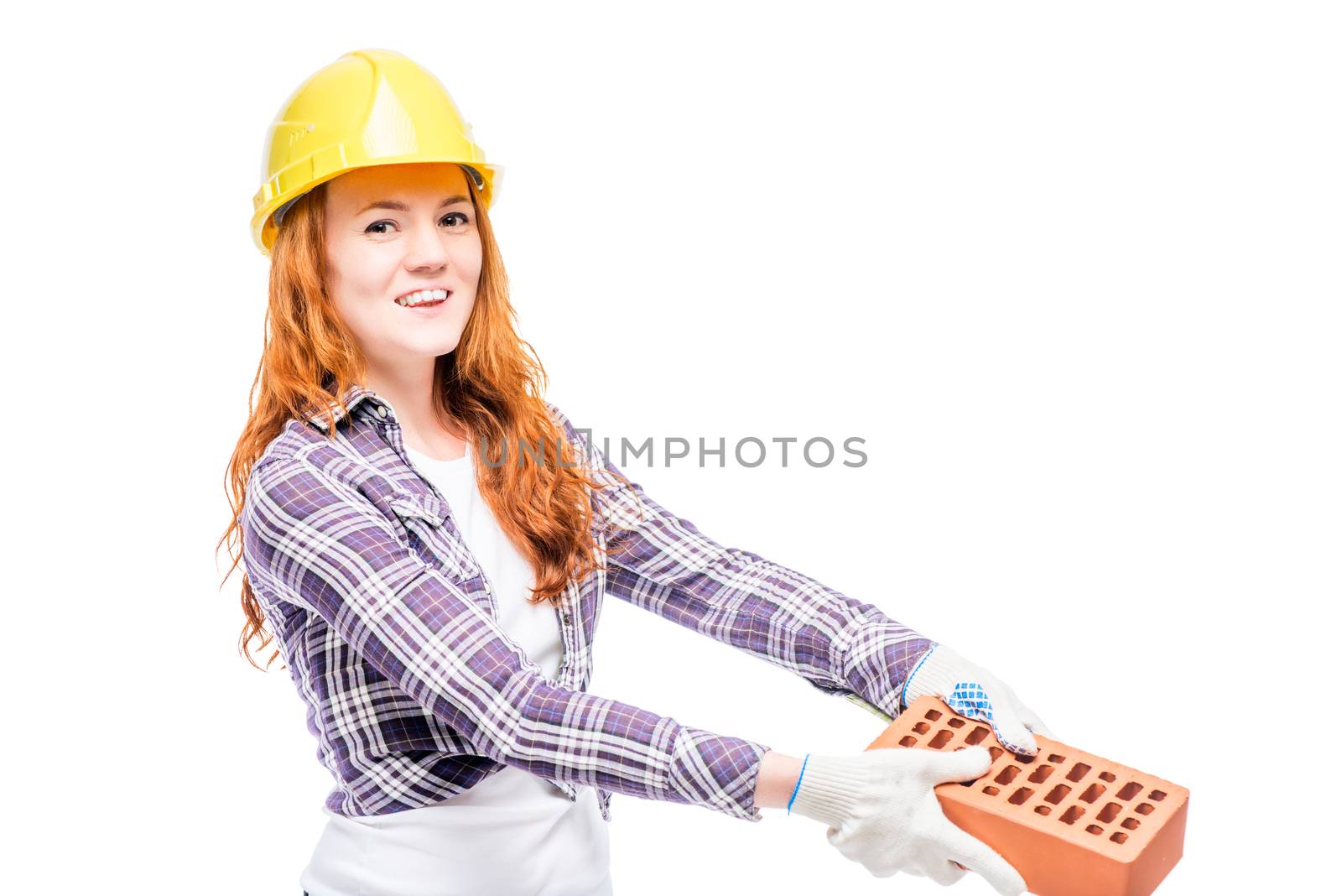 beautiful woman with red hair holds a brick, wearing a yellow helmet on her head