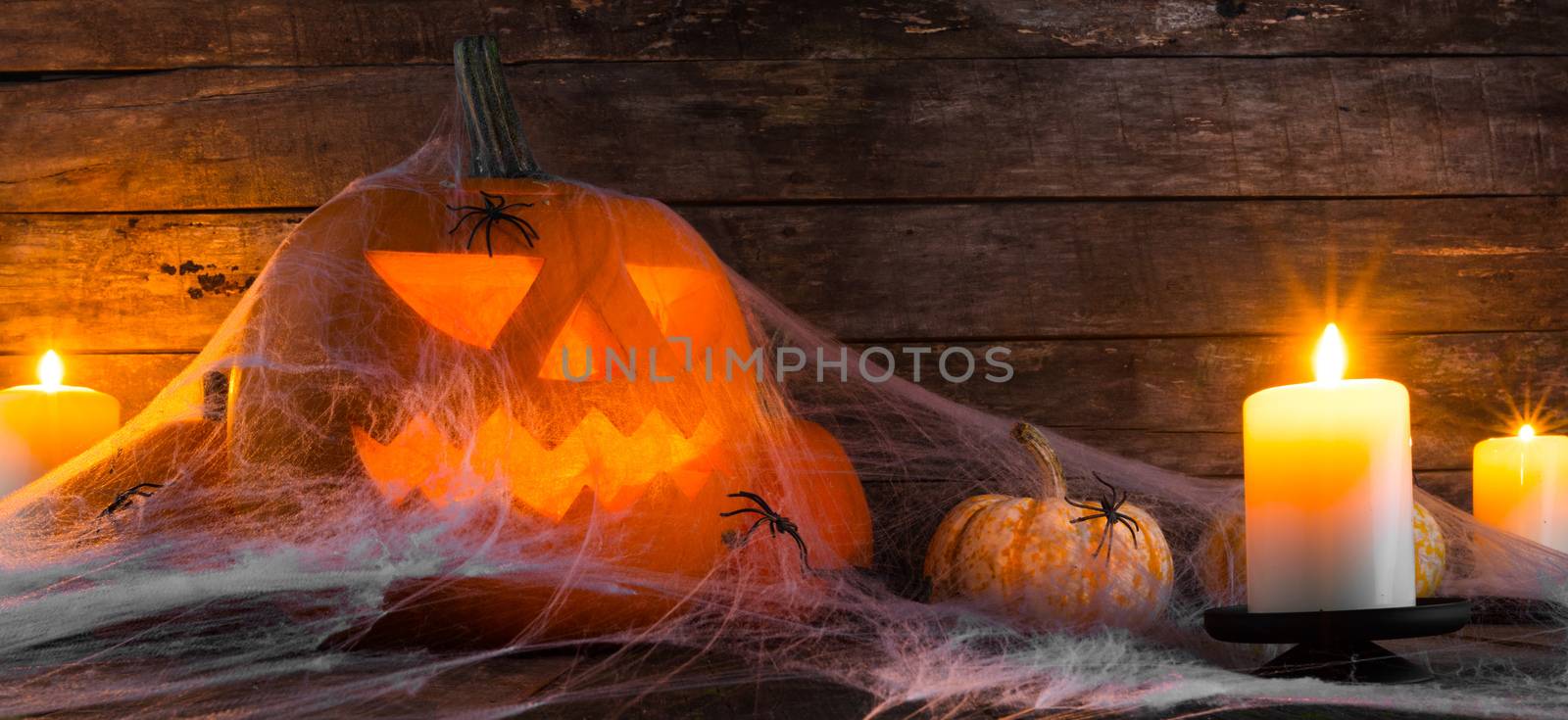 Jack O Lantern Halloween pumpkin, spiders on web and burning candles