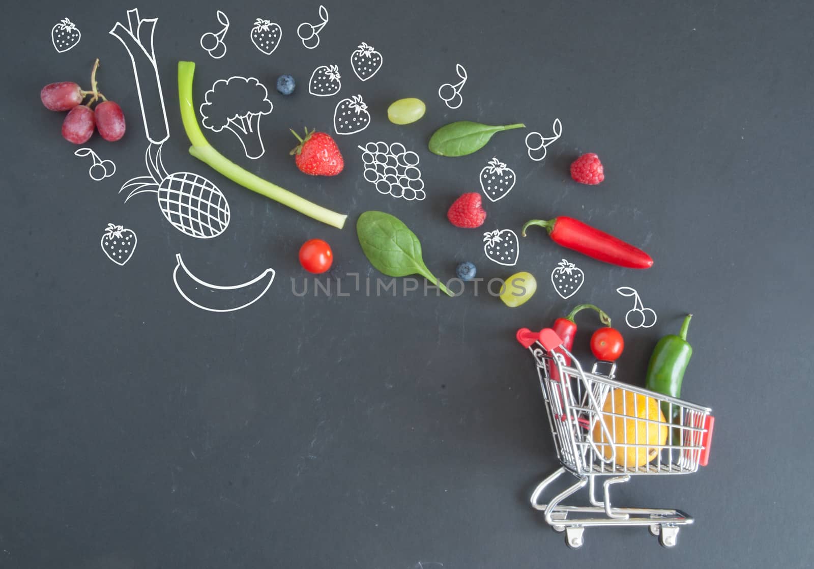 Grocery shopping cart filled with fruits and vegetables and sketches on a chalkboard 