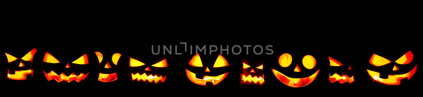 Many Halloween Pumpkin glowing faces in a row isolated on black background