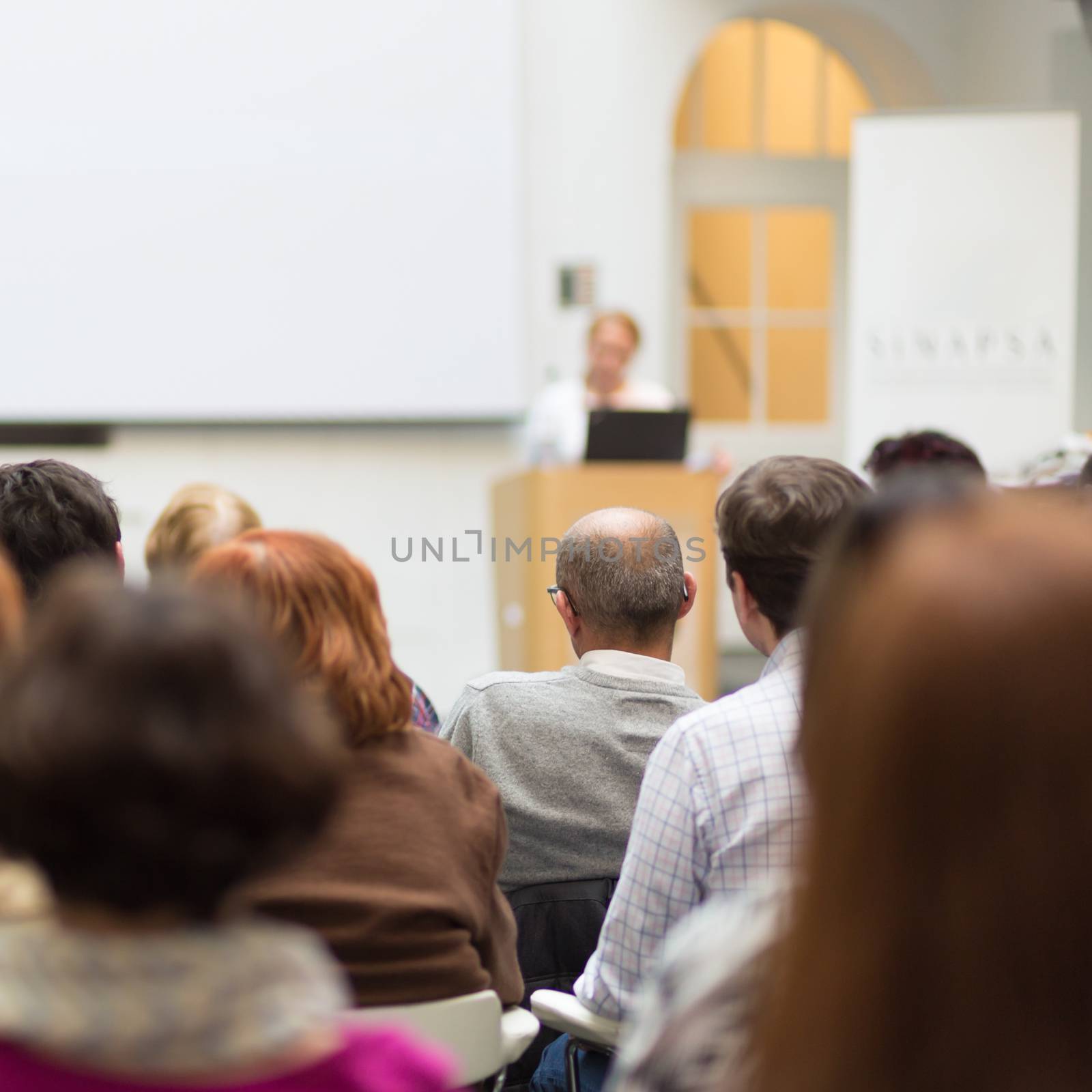 Woman giving presentation in lecture hall at university. by kasto