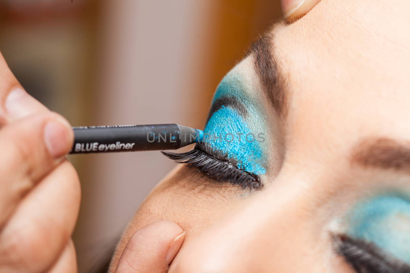 Makeup artist applying blue eyeshadow on white woman eyes