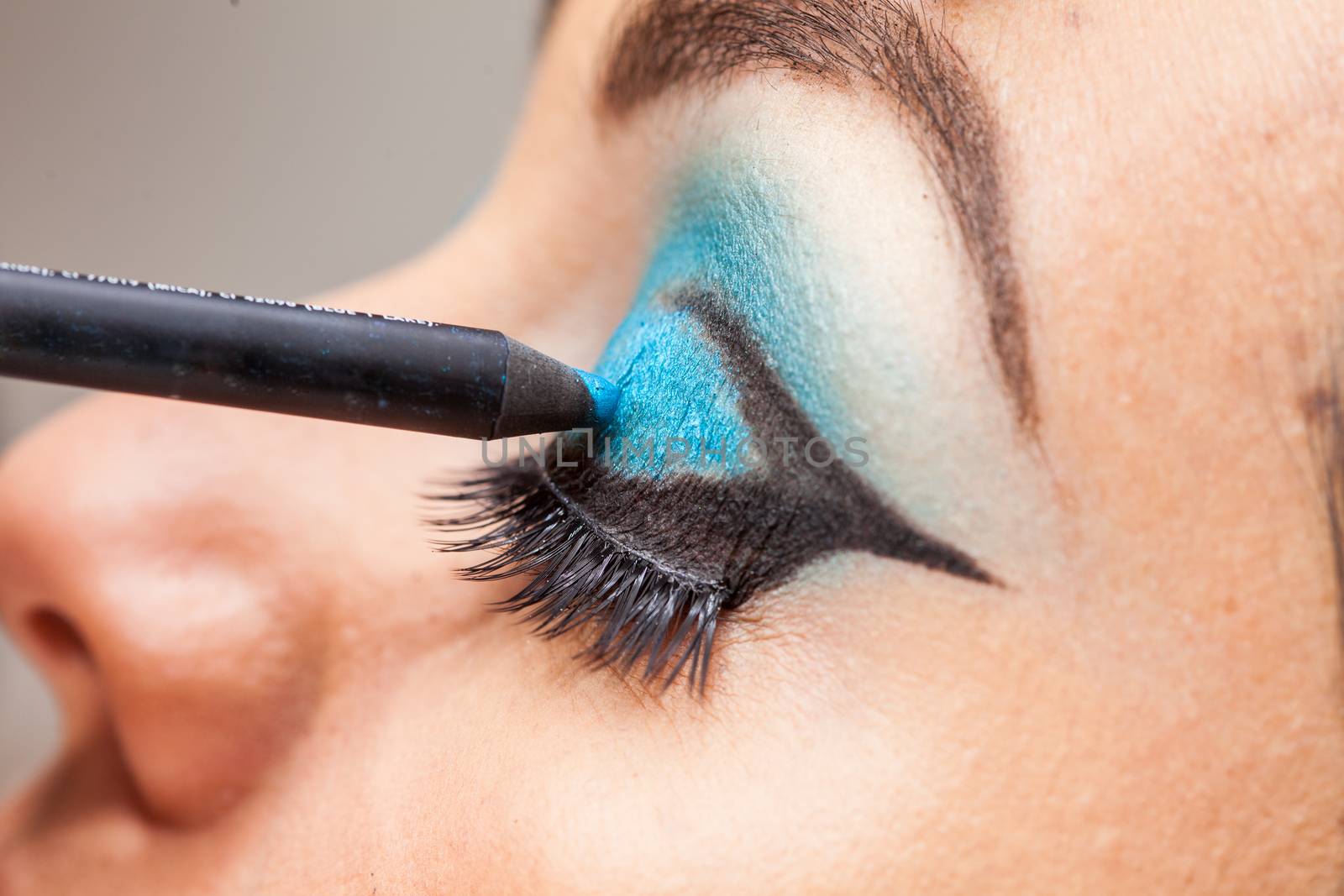 Makeup artist applying blue eyeshadow on white woman eyes