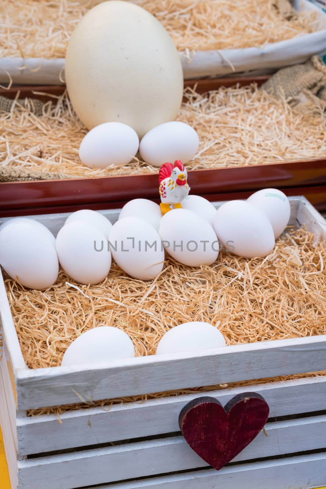 White chicken eggs leaning on straw in wooden basket