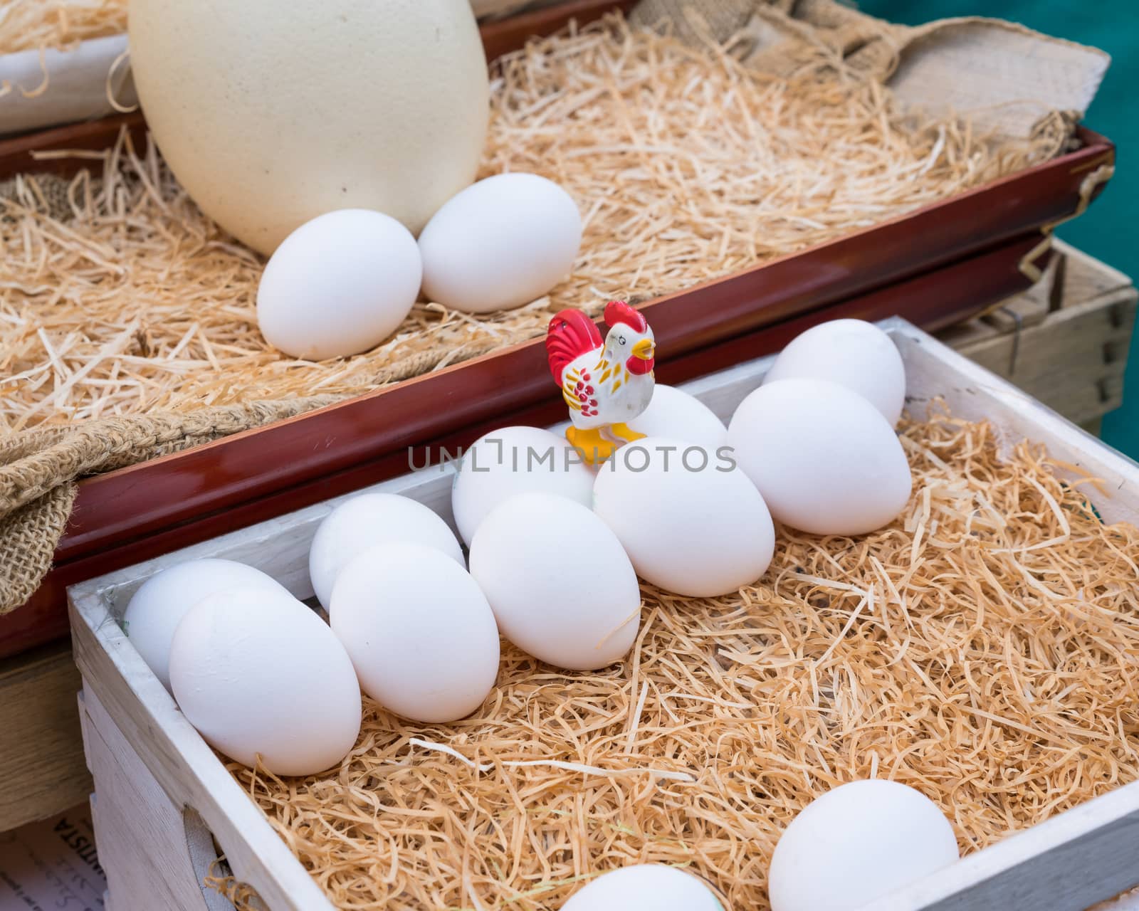 White chicken eggs leaning on straw in wooden basket