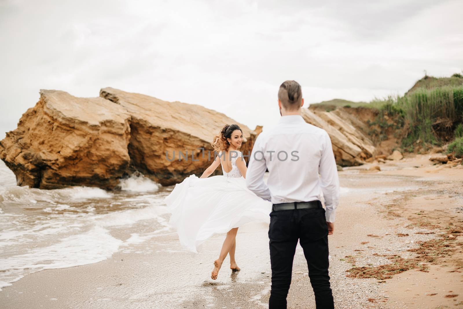 young couple groom with the bride on a sandy beach at a wedding walk