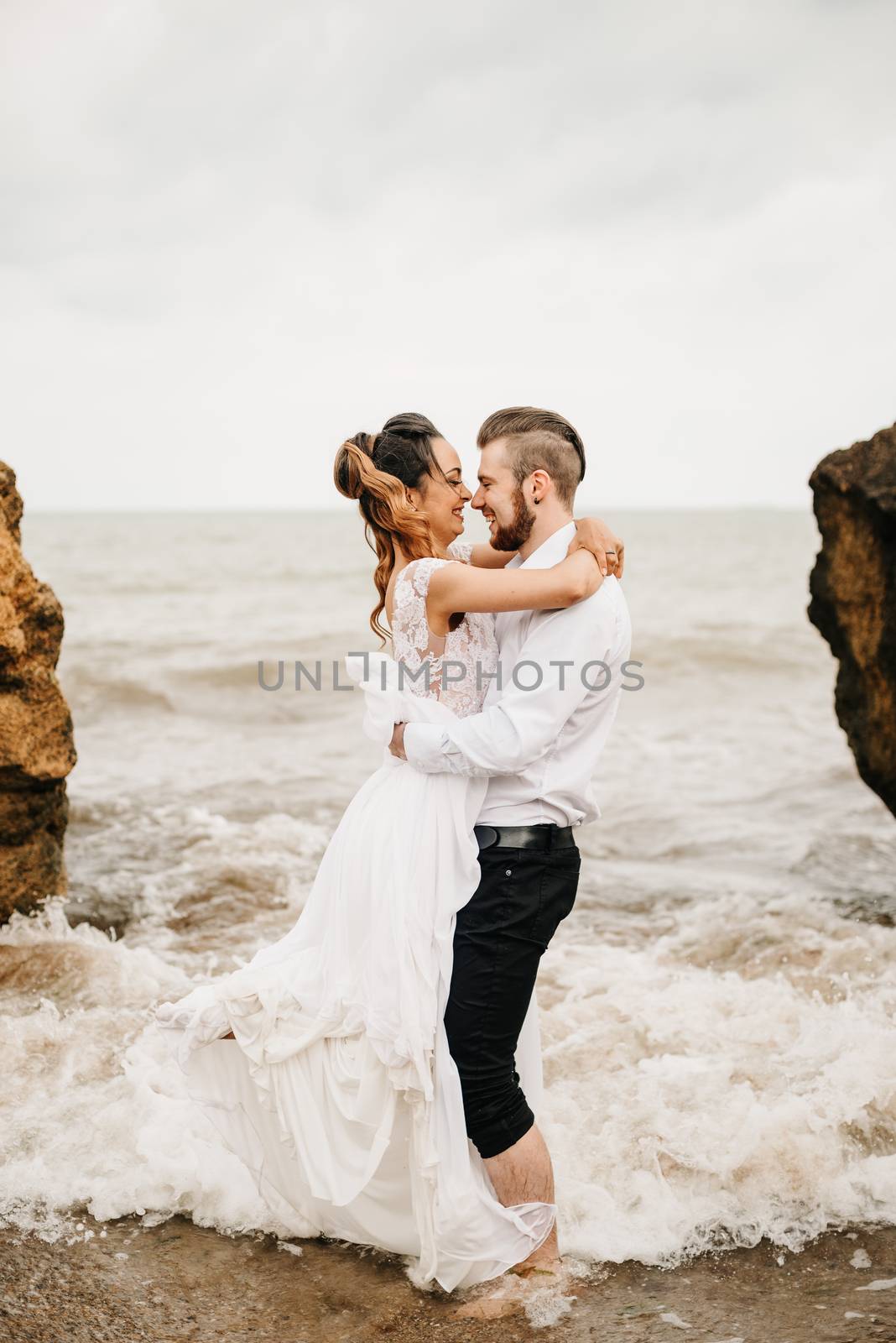 young couple groom with the bride on a sandy beach at a wedding walk