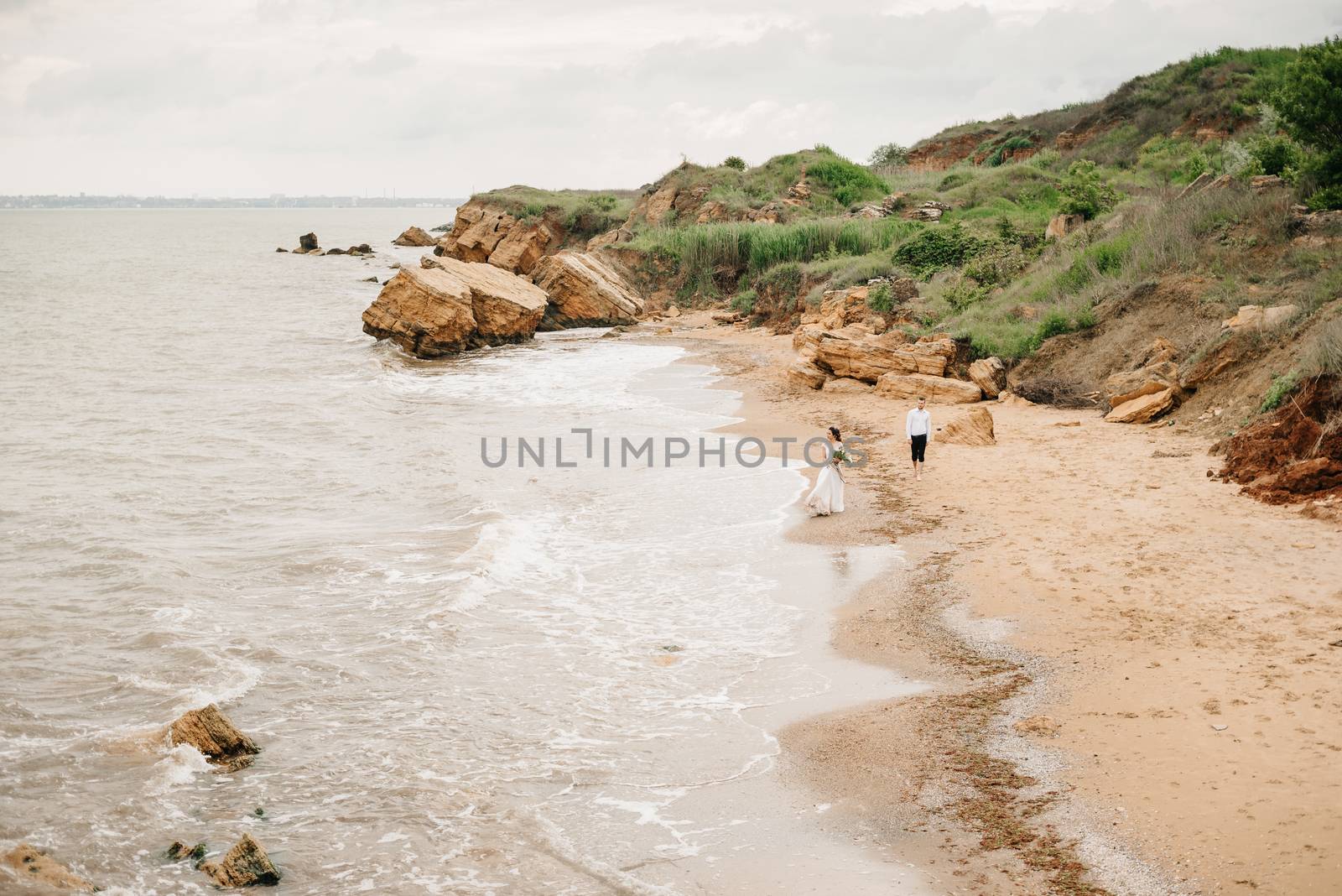 young couple groom with the bride on a sandy beach at a wedding walk