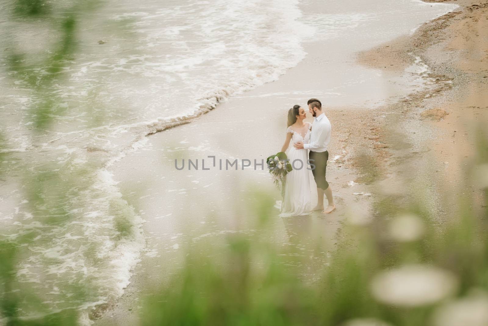 young couple groom with the bride on a sandy beach at a wedding walk