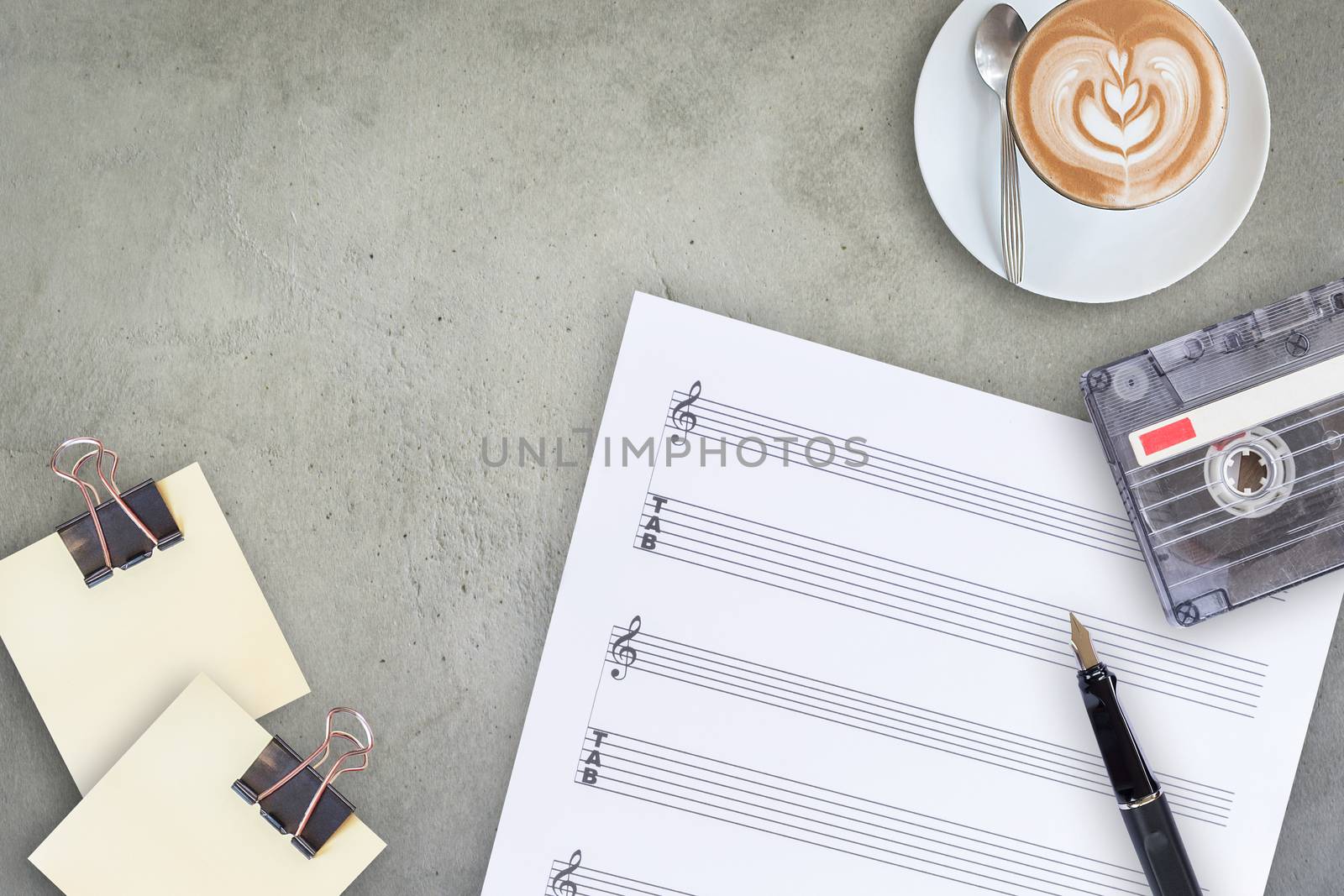 Sheet music, fountain pen, tape cassette and coffee latte on wooden table, top view picture