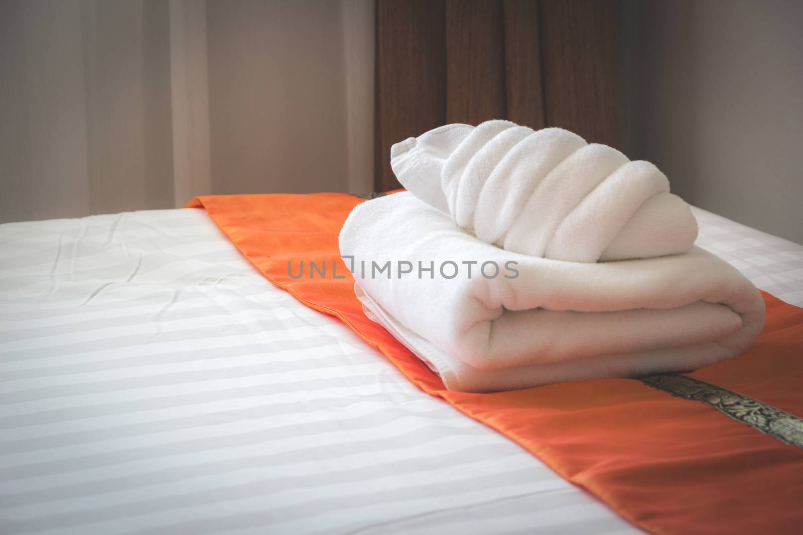 white bed with fresh white bath towel in the room