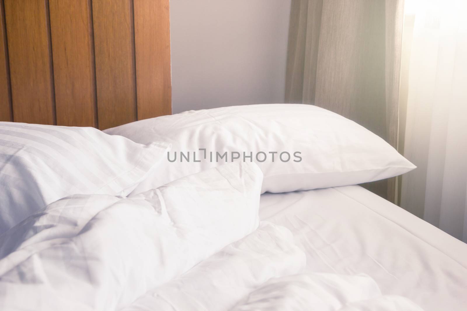 white pillow and blanket with wrinkle messy on bed in bedroom with lighting upper left side, from sleeping in a long night winter.