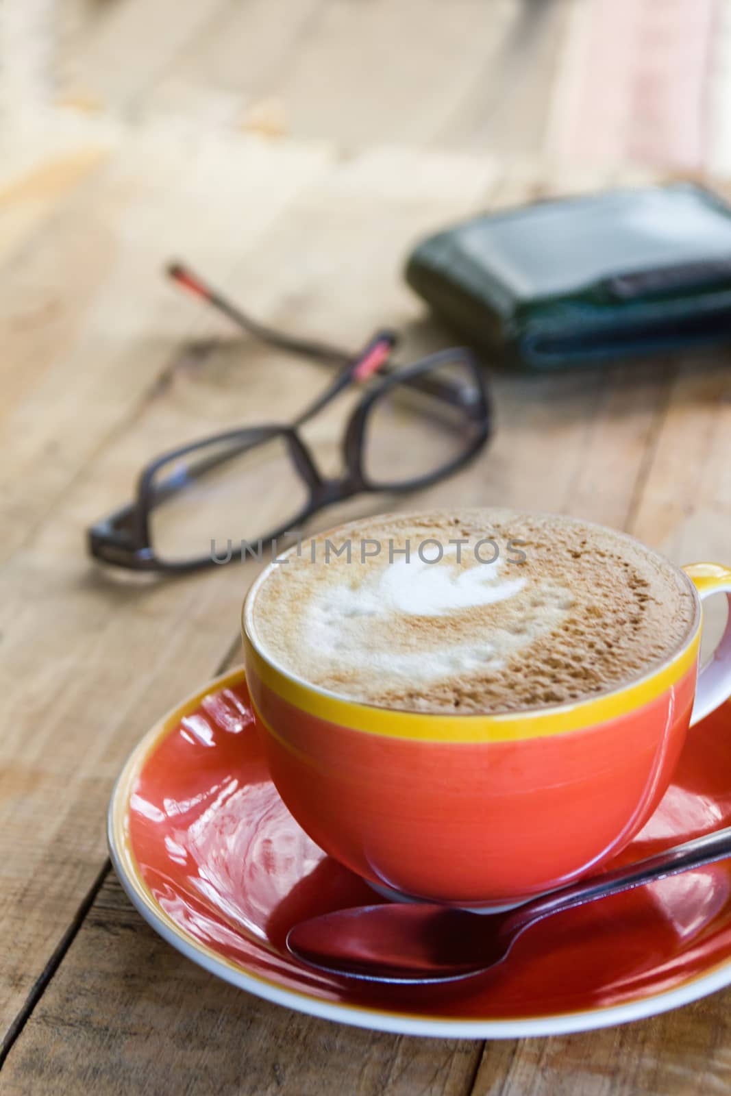 orange cup of coffee latte art with leaf pattern on wooden backg by rakoptonLPN