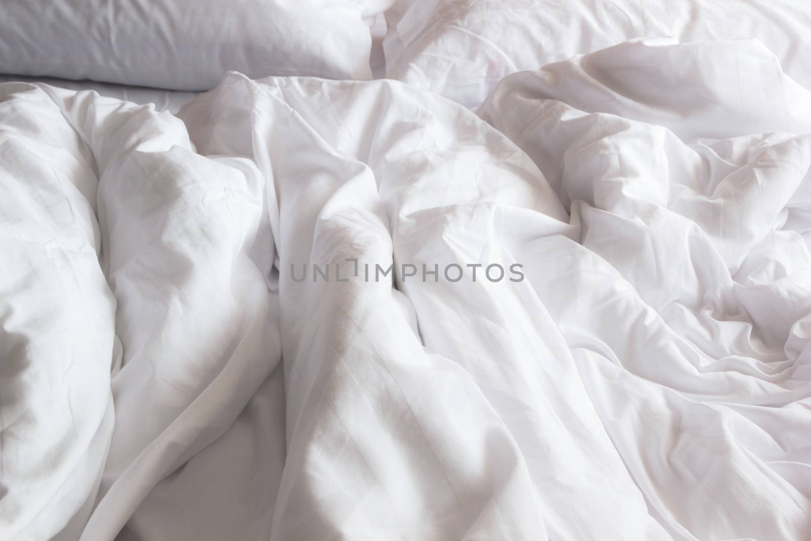 top view of white pillow on bed and with wrinkle messy blanket in bedroom, from sleeping in a long night.