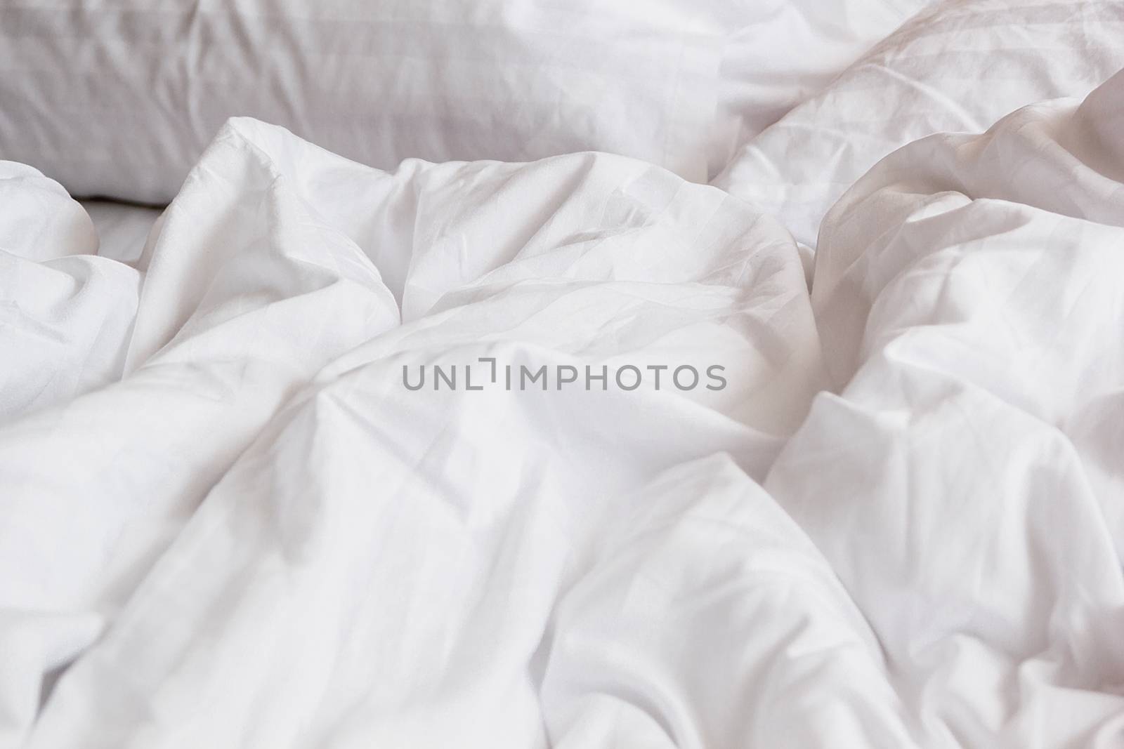 top view of white pillow on bed and with wrinkle messy blanket in bedroom, from sleeping in a long night.