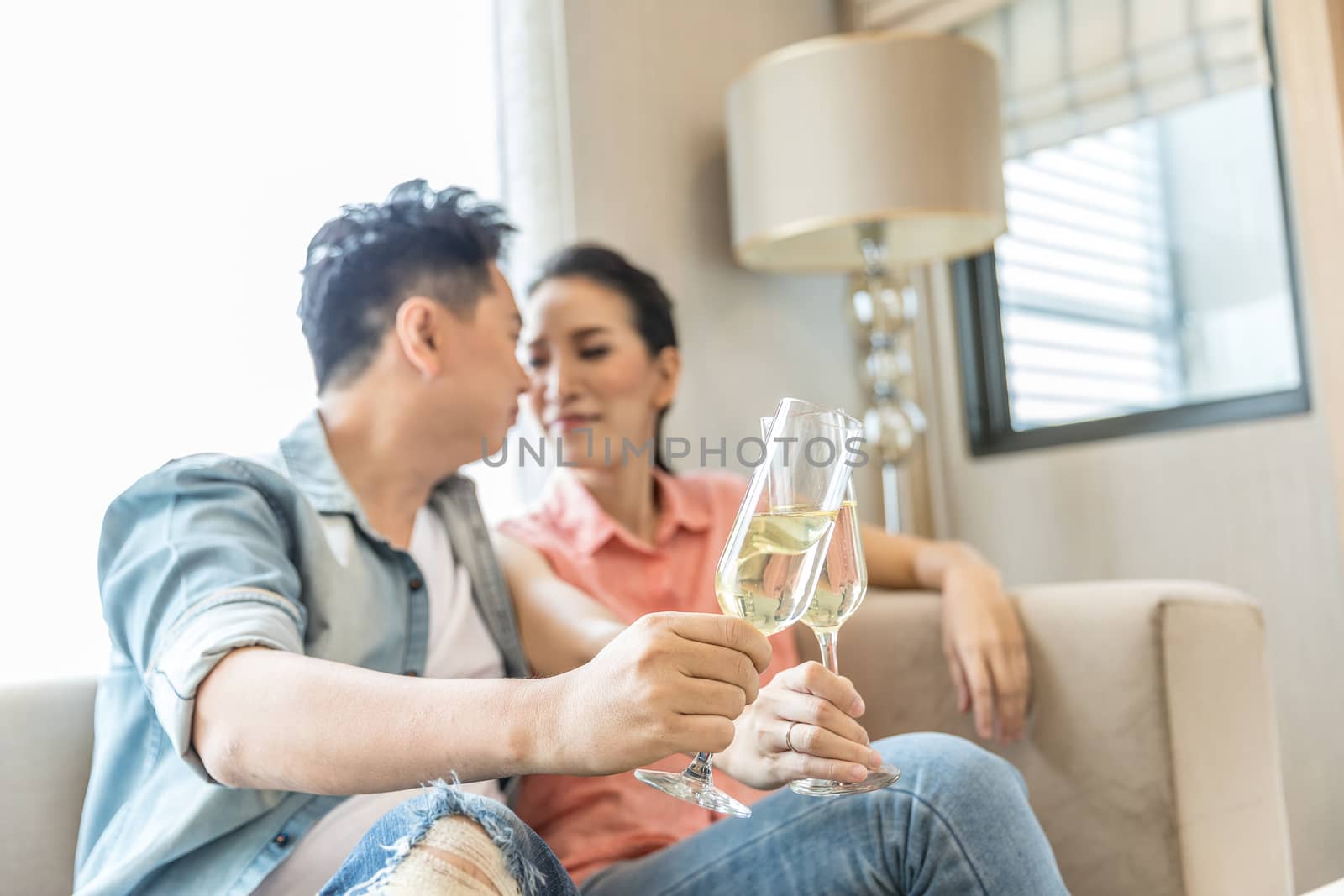 Young Couples celebrate together with wine  in bedroom of contemporary house for modern lifestyle concept (Focus at glasses)