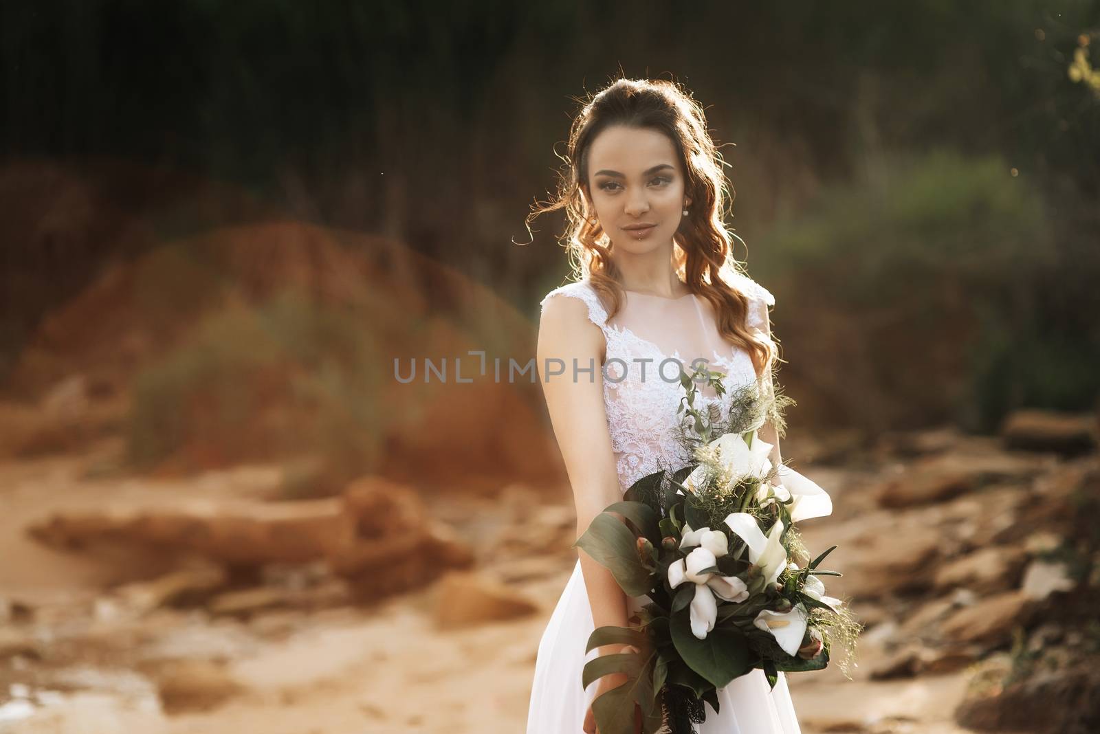 bride with a wedding bouquet on the shore of the black sea in the sunset light