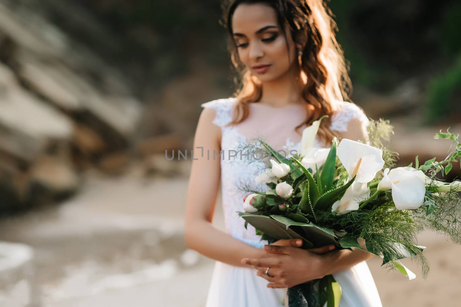 bride with a wedding bouquet on the shore of the black sea in the sunset light