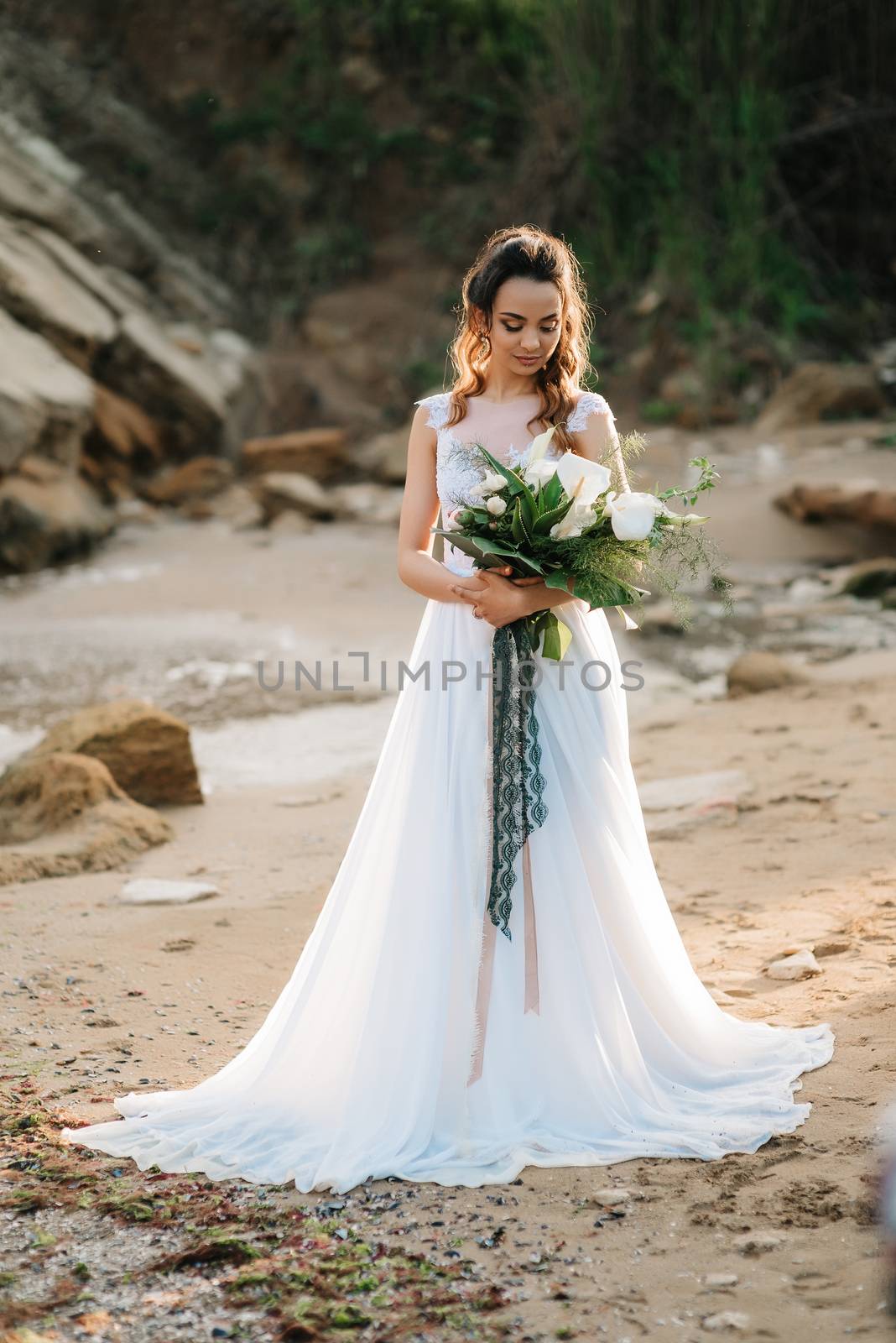 bride with a wedding bouquet on the shore of the black sea in the sunset light