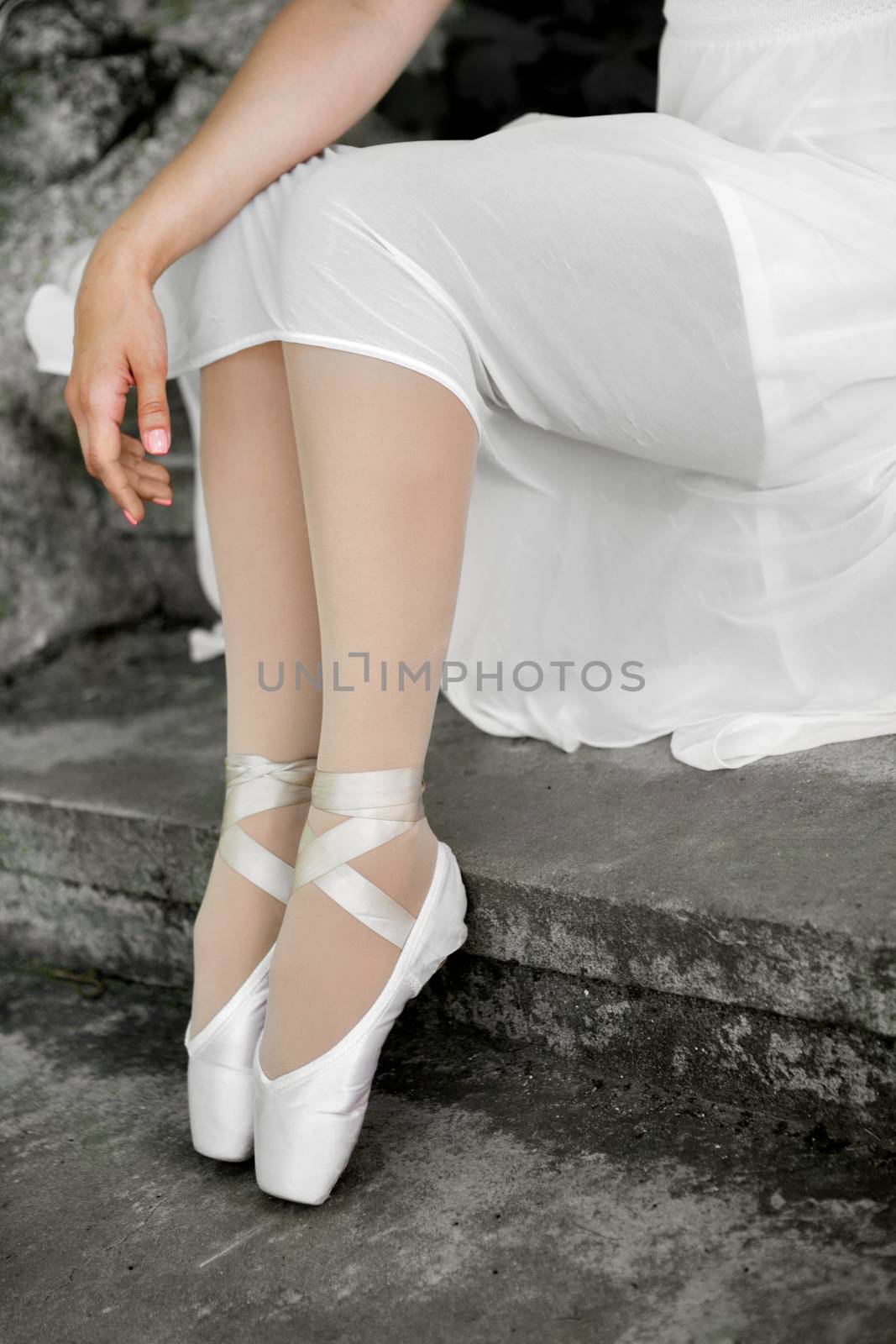 Legs of a beautiful ballerina close-up. Pointe shoes on concrete stairs