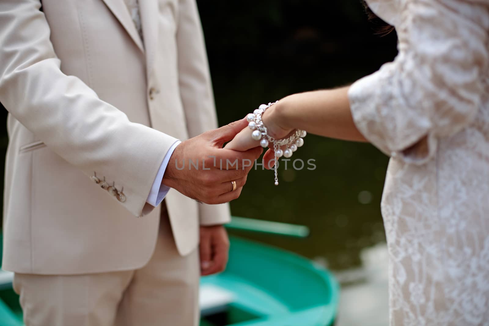 The groom gently holds the bride by the hand, close-up