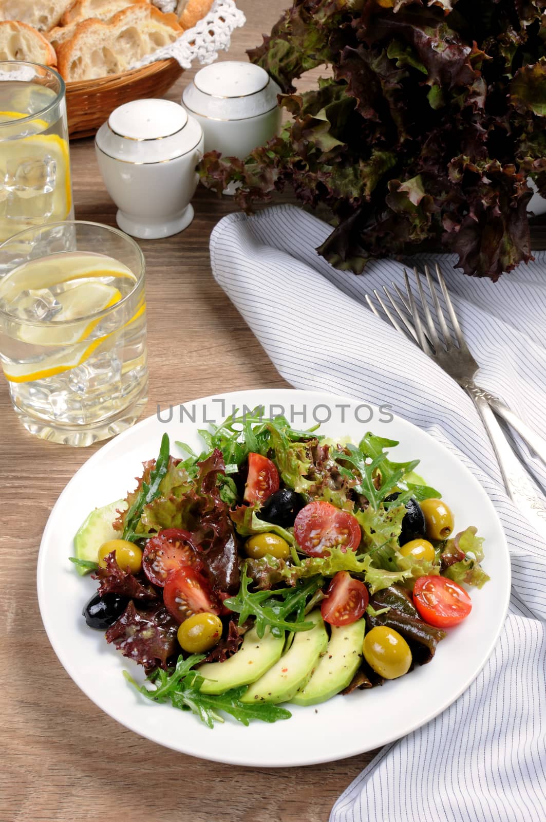 Summer salad - with avocado, olives, tomatoes in lettuce dressed, mustard-garlic sauce