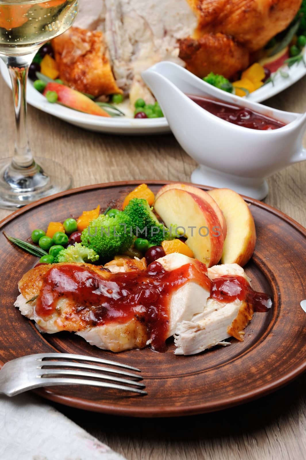 Slices of baked turkey with cranberry-orange sauce with fruit and vegetable garnish